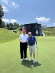 Gali būti 2 žmonės, žmonės žaidžia golfą, golfo vežimėlis, golfo aikštynas ir tekstas vaizdas